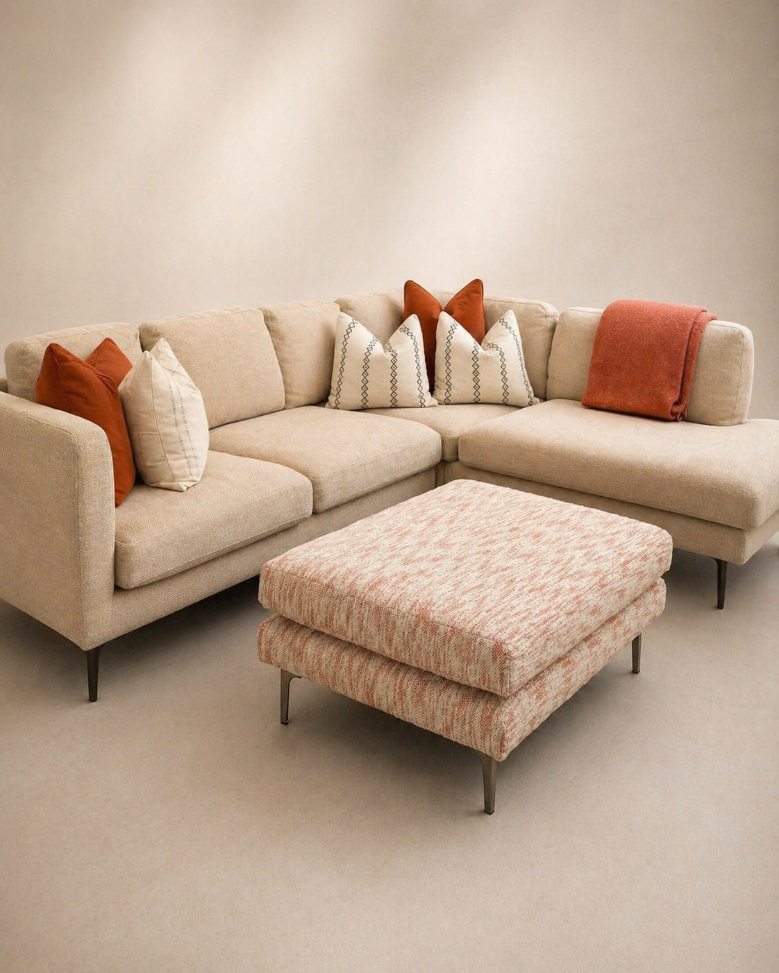 Cream sectional sofa with terracotta cushions and patterned ottoman